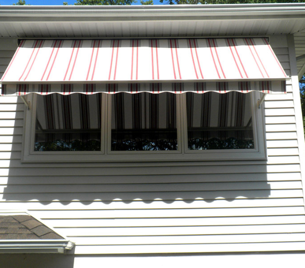 A white house with a red and white striped Novita awning
