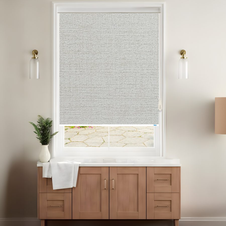A stylish room features a grey blackout venice roller blinds covering a window with a view of a stone patio, complemented by modern decor.