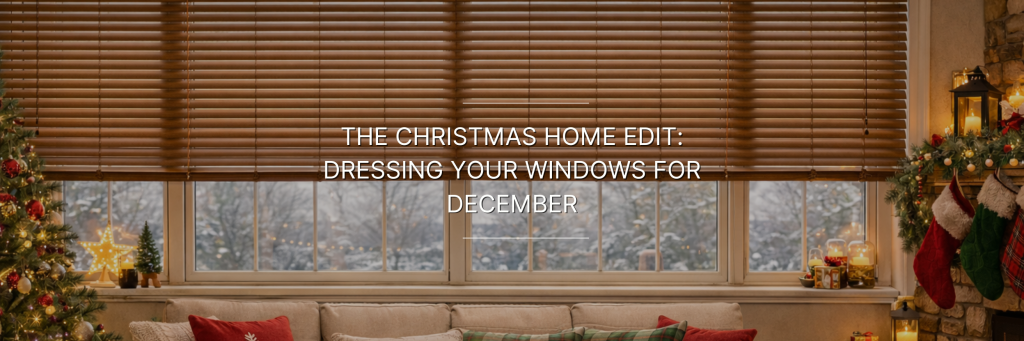 A cozy living room with a large window displaying a snowy view. Wooden blinds are partially down, and festive decor includes a Christmas tree and stockings.